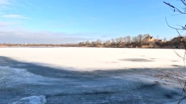 winter sunny landscape on the river bank. Beautiful scenic landscape view of a calm river flowing on a bright sunny clear blue sky. Dnieper river in winter. Ukrainian winter landscape. River bank and ice.