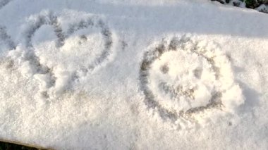drawing in the snow. man draw on the snow. Child drawing heart shape on snow. Female Hand with Nice Manicure Drawing a Heart on White Fluffy Snow in Forest. Hand touches the snow. Sunny winter day.