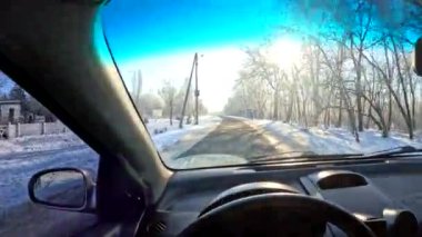 the driver is driving. from the first person. winter road. travel in winter. inside the car. dirty windshield. the driver is holding the steering wheel. sunny day and transport. transport on the road in winter.