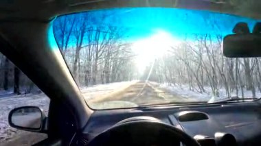 the driver is driving. from the first person. winter road. travel in winter. inside the car. dirty windshield. the driver is holding the steering wheel. sunny day and transport. transport on the road in winter.