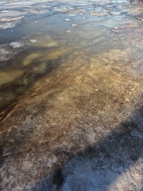 clear ice on the river. ice texture. the ice is melting. spring thaw. frozen water. air and water.
