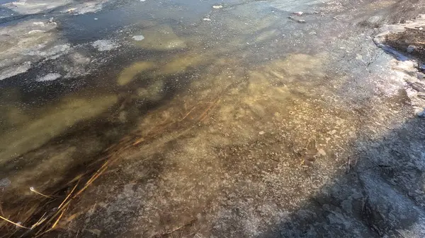 clear ice on the river. ice texture. the ice is melting. spring thaw. frozen water. air and water.
