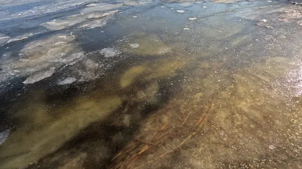 clear ice on the river. ice texture. the ice is melting. spring thaw. frozen water. air and water.