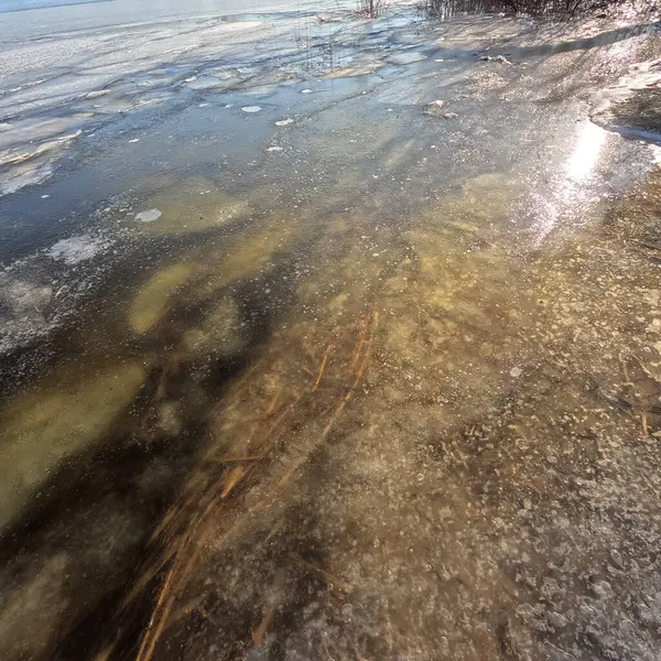 clear ice on the river. ice texture. the ice is melting. spring thaw. frozen water. air and water.