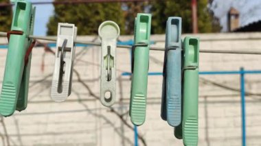 İpte çok renkli mandallar var. Tarafsız yeşil zeminde çiy damlaları olan mavi mandallar, beyaz telde mandallar, çamaşır ipi kurutma teli, çok renkli mandallar..