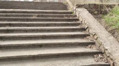 Eski beton merdivenler. Merdivenlerde kuru yapraklar var. Kameralar kuru meşe yapraklarıyla kaplı merdivenlerden yukarı kayıyor. Ağır çekim yakın çekim. Yerde yatan sonbahar yeşilliğinin ayrıntılı hareketli görüntüsü.