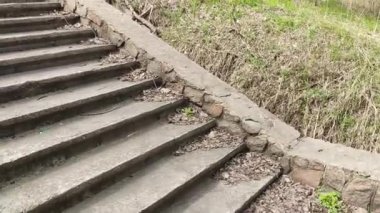 Eski beton merdivenler. Merdivenlerde kuru yapraklar var. Kameralar kuru meşe yapraklarıyla kaplı merdivenlerden yukarı kayıyor. Ağır çekim yakın çekim. Yerde yatan sonbahar yeşilliğinin ayrıntılı hareketli görüntüsü.