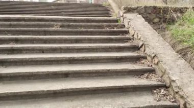 Eski beton merdivenler. Merdivenlerde kuru yapraklar var. Kameralar kuru meşe yapraklarıyla kaplı merdivenlerden yukarı kayıyor. Ağır çekim yakın çekim. Yerde yatan sonbahar yeşilliğinin ayrıntılı hareketli görüntüsü.