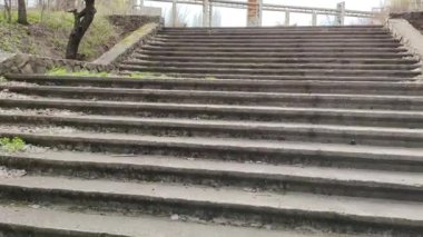 Eski beton merdivenler. Merdivenlerde kuru yapraklar var. Kameralar kuru meşe yapraklarıyla kaplı merdivenlerden yukarı kayıyor. Ağır çekim yakın çekim. Yerde yatan sonbahar yeşilliğinin ayrıntılı hareketli görüntüsü.