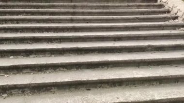 Eski beton merdivenler. Merdivenlerde kuru yapraklar var. Kameralar kuru meşe yapraklarıyla kaplı merdivenlerden yukarı kayıyor. Ağır çekim yakın çekim. Yerde yatan sonbahar yeşilliğinin ayrıntılı hareketli görüntüsü.