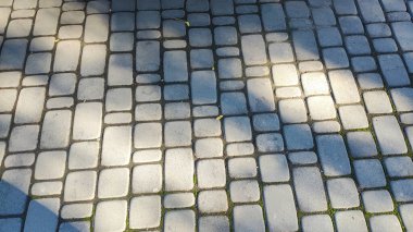 Döşeme taşları. Tuğla deseni. Taştan yapılmış bir yol. Döşeme taşlarının dokusu. Asfaltlı bir caddenin taşlarında yavaş dairesel hareketler. Şehir parkında kaldırım taşlarından yapılmış bir kaldırım.