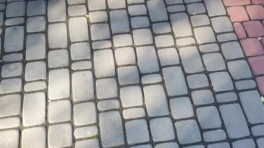 Döşeme taşları. Tuğla deseni. Taştan yapılmış bir yol. Döşeme taşlarının dokusu. Asfaltlı bir caddenin taşlarında yavaş dairesel hareketler. Şehir parkında kaldırım taşlarından yapılmış bir kaldırım.