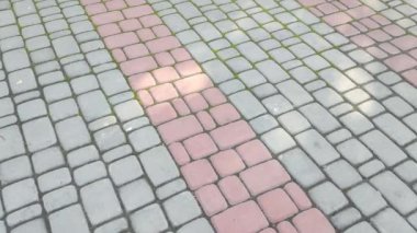 Döşeme taşları. Tuğla deseni. Taştan yapılmış bir yol. Döşeme taşlarının dokusu. Asfaltlı bir caddenin taşlarında yavaş dairesel hareketler. Şehir parkında kaldırım taşlarından yapılmış bir kaldırım.