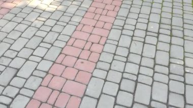 Döşeme taşları. Tuğla deseni. Taştan yapılmış bir yol. Döşeme taşlarının dokusu. Asfaltlı bir caddenin taşlarında yavaş dairesel hareketler. Şehir parkında kaldırım taşlarından yapılmış bir kaldırım.