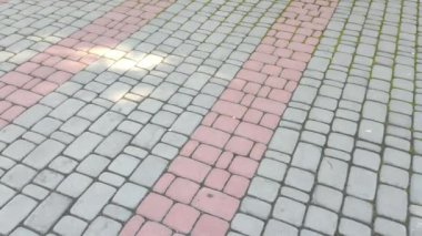 Döşeme taşları. Tuğla deseni. Taştan yapılmış bir yol. Döşeme taşlarının dokusu. Asfaltlı bir caddenin taşlarında yavaş dairesel hareketler. Şehir parkında kaldırım taşlarından yapılmış bir kaldırım.