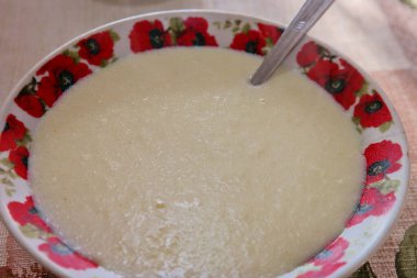 Kaşık ve irmik lapası. Yağlı tereyağını irmikli sütlü yulaf lapasıyla kaseye koymak, sıcak ve sağlıklı geleneksel kahvaltı. Yüksek açı. Sağlıklı kahvaltı. Sütlü lapa. beyaz haşlanmış yulaf lapası