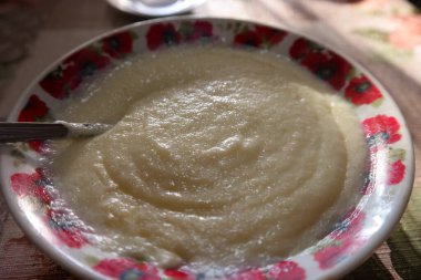 Kaşık ve irmik lapası. Yağlı tereyağını irmikli sütlü yulaf lapasıyla kaseye koymak, sıcak ve sağlıklı geleneksel kahvaltı. Yüksek açı. Sağlıklı kahvaltı. Sütlü lapa. beyaz haşlanmış yulaf lapası