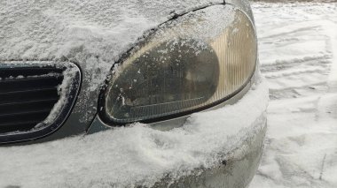 Arabada kar var. Araba karda sıkıştı kaldı. Arabanın farları donduğu için dondu. Araba farları kışın dışarı park ettikten sonra buzla kaplandı. Arabanın farının camında ince bir buz tabakası.