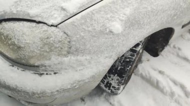 Arabada kar var. Araba karda sıkıştı kaldı. Arabanın farları donduğu için dondu. Araba farları kışın dışarı park ettikten sonra buzla kaplandı. Arabanın farının camında ince bir buz tabakası.