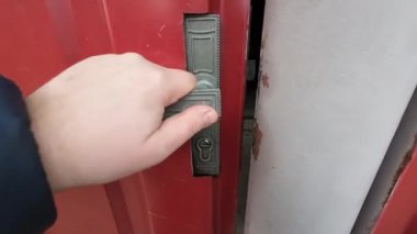 Eller kapı kolunu açar. Yakından erkek eli açık kapı kolu ve tanınmayan bir adam kapanış kapısına giriyor. Beyaz bir genç evin içinde yürüyor. Kapı kolunu tutuyorum..