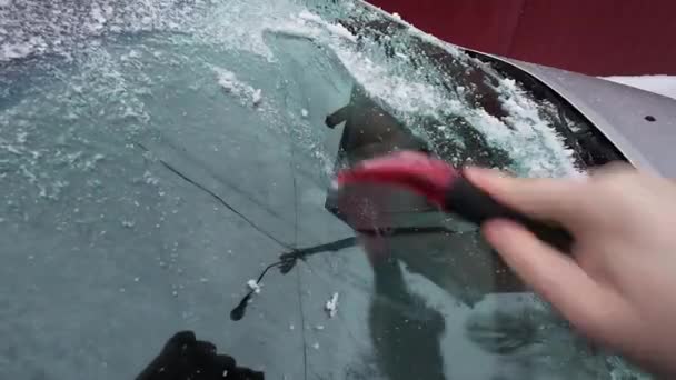 車窓から氷を掃除する男 雪の嵐の吹雪の後の車窓から新雪をブラッシングする人 寒い冬の天候で車の所有者の朝のルーチンの困難 車の窓のクリーニング — ストック動画