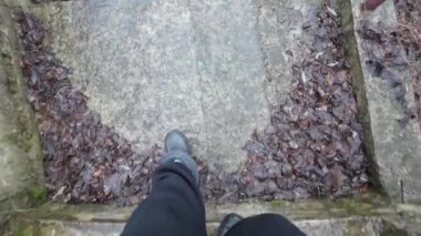 Eski taş merdiven. Bir adam merdivenlerden çıkıyor. Siyah spor ayakkabılı bir adamın bacakları eski bir taş merdiven boyunca yürüyor. Merdivenlerden uzun bir yürüyüş. - Yakın çekim. 4k video