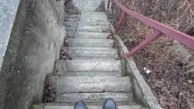 Eski taş merdiven. Bir adam merdivenlerden çıkıyor. Siyah spor ayakkabılı bir adamın bacakları eski bir taş merdiven boyunca yürüyor. Merdivenlerden uzun bir yürüyüş. - Yakın çekim. 4k video