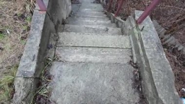 Eski taş merdiven. Bir adam merdivenlerden çıkıyor. Siyah spor ayakkabılı bir adamın bacakları eski bir taş merdiven boyunca yürüyor. Merdivenlerden uzun bir yürüyüş. - Yakın çekim. 4k video
