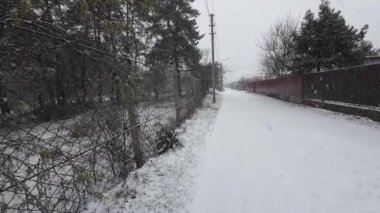 Dışarıda kar yağıyor. Karda küçük bir kasabanın caddesi. Kış atmosferi. Kar yağışı. Gökyüzünden büyük kar taneleri.