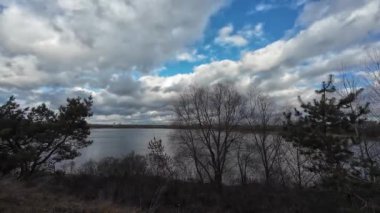 Nehir kıyısında bulutlu bir manzara. Su ve bulutlar. Bulutlu hava manzarası. Dnepr Nehri. Ukrayna. Sonbahar akşamı manzarası. Su ve gökyüzü. Renkli gökyüzü ve ağaçlar durgun sulara yansıyor.