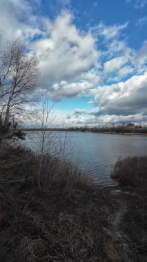Nehir kıyısında bulutlu bir manzara. Su ve bulutlar. Bulutlu hava manzarası. Dnepr Nehri. Ukrayna. Sonbahar akşamı manzarası. Su ve gökyüzü. Renkli gökyüzü ve ağaçlar durgun sulara yansıyor.