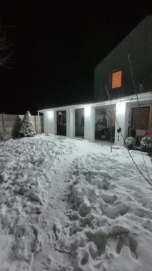 Karda veranda. Geceleri karlı bir bahçe. Şiddetli bir kar yağışı sırasında geceleri arka bahçedeki taraça. Kış sahnesi. Karla kaplı bir gece konutu. Kar yağıyor.