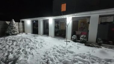 Karda veranda. Geceleri karlı bir bahçe. Şiddetli bir kar yağışı sırasında geceleri arka bahçedeki taraça. Kış sahnesi. Karla kaplı bir gece konutu. Kar yağıyor.