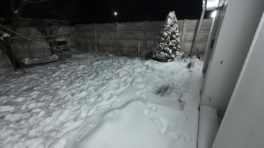 Karda veranda. Geceleri karlı bir bahçe. Şiddetli bir kar yağışı sırasında geceleri arka bahçedeki taraça. Kış sahnesi. Karla kaplı bir gece konutu. Kar yağıyor.