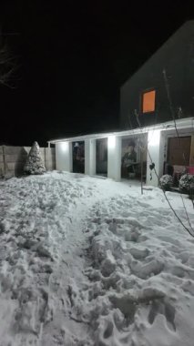 Karda veranda. Geceleri karlı bir bahçe. Şiddetli bir kar yağışı sırasında geceleri arka bahçedeki taraça. Kış sahnesi. Karla kaplı bir gece konutu. Kar yağıyor.