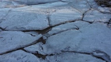 Nehirdeki buz. Donmuş nehirde yürü. Bir adam kar ve buz üzerinde yürür. Tehlikeli buz. dondurucu su. Buzda derin çatlaklar var. Nehirli güneşli kış manzarası. Kış nehri ve güneş.