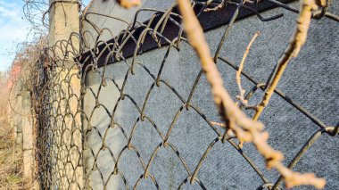 Çit örgüsü. Güneşin doğuşuyla birlikte güneş ışınları tel örgülerden geçer. Bölgeyi geçitten korur, hareketi engeller, sınırı işaretler. Çitteki metal tel..