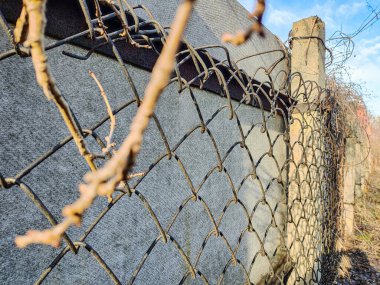 Çit örgüsü. Güneşin doğuşuyla birlikte güneş ışınları tel örgülerden geçer. Bölgeyi geçitten korur, hareketi engeller, sınırı işaretler. Çitteki metal tel..