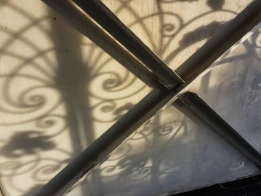 Duvardaki güzel gölgeler. Açık iş gölgeleri. Şehirde günbatımı. Demir ızgaraların ve beyaz duvardaki ağaçların uzun gölgeleri, yıpranmış duvar arka planının beyaz dokusuna doğal gölgeler örtülür..