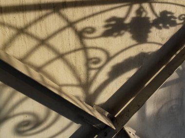 Duvardaki güzel gölgeler. Açık iş gölgeleri. Şehirde günbatımı. Demir ızgaraların ve beyaz duvardaki ağaçların uzun gölgeleri, yıpranmış duvar arka planının beyaz dokusuna doğal gölgeler örtülür..