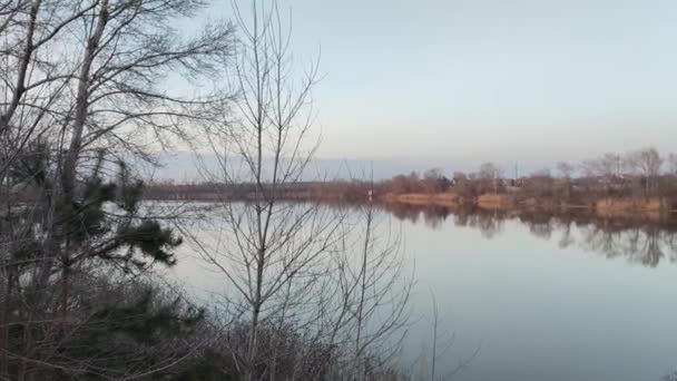 在河上的黄昏景观 水面上倒影 多彩的云天和树木映衬在平静的河水中 河岸上长满了草和树 房子反映在水里 — 图库视频影像
