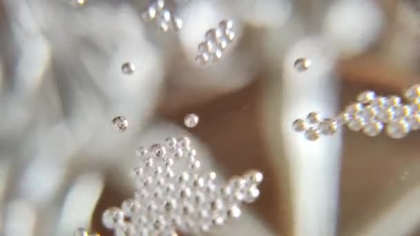 バブルマクロビデオ シャンパンの泡 黄色の背景にマージする抽象的な透明な泡のフロントビュー シャンパンガラスで発熱泡のトップビュークローズアップ — ストック動画