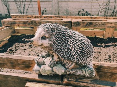 Kirpinin bahçe heykelciği. Kehribar kirpisi bir sehpanın üzerinde. Oyuncak kirpi. Bahçe dekoru. Sokak dekoru. retro biçimi.