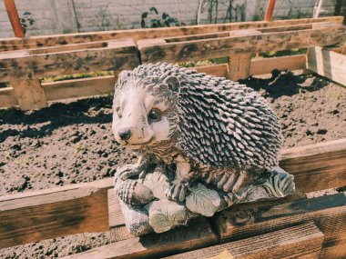 Kirpinin bahçe heykelciği. Kehribar kirpisi bir sehpanın üzerinde. Oyuncak kirpi. Bahçe dekoru. Sokak dekoru. retro biçimi.