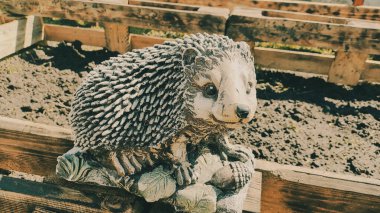 Kirpinin bahçe heykelciği. Kehribar kirpisi bir sehpanın üzerinde. Oyuncak kirpi. Bahçe dekoru. Sokak dekoru. retro biçimi.