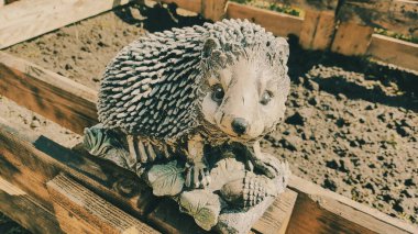 Kirpinin bahçe heykelciği. Kehribar kirpisi bir sehpanın üzerinde. Oyuncak kirpi. Bahçe dekoru. Sokak dekoru. retro biçimi.