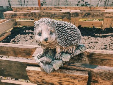 Kirpinin bahçe heykelciği. Kehribar kirpisi bir sehpanın üzerinde. Oyuncak kirpi. Bahçe dekoru. Sokak dekoru. retro biçimi.