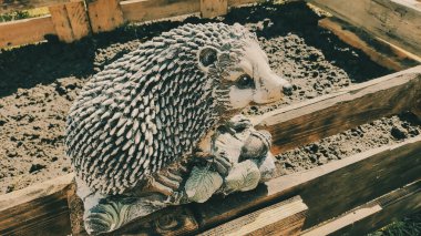 Kirpinin bahçe heykelciği. Kehribar kirpisi bir sehpanın üzerinde. Oyuncak kirpi. Bahçe dekoru. Sokak dekoru. retro biçimi.