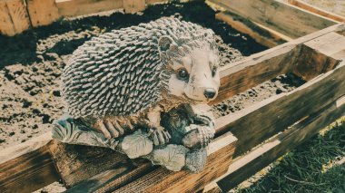 Kirpinin bahçe heykelciği. Kehribar kirpisi bir sehpanın üzerinde. Oyuncak kirpi. Bahçe dekoru. Sokak dekoru. retro biçimi.