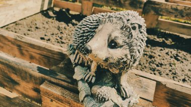 Kirpinin bahçe heykelciği. Kehribar kirpisi bir sehpanın üzerinde. Oyuncak kirpi. Bahçe dekoru. Sokak dekoru. retro biçimi.